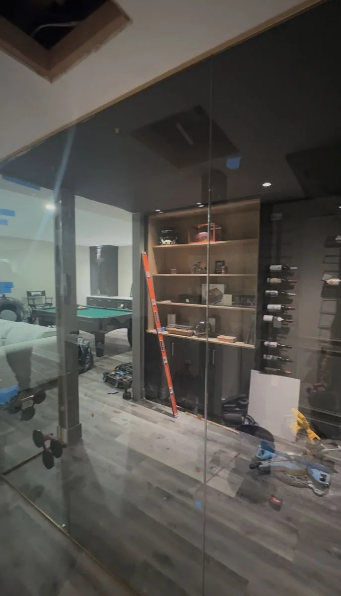 Finished custom glass panel room — wine display wall, open shelving, glass partition with gold hardware