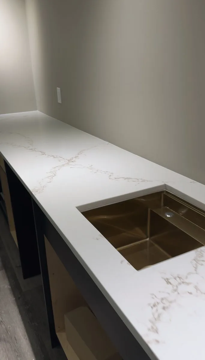 Finished bar area — quartz countertop with gold undermount bar sink, custom dark cabinetry