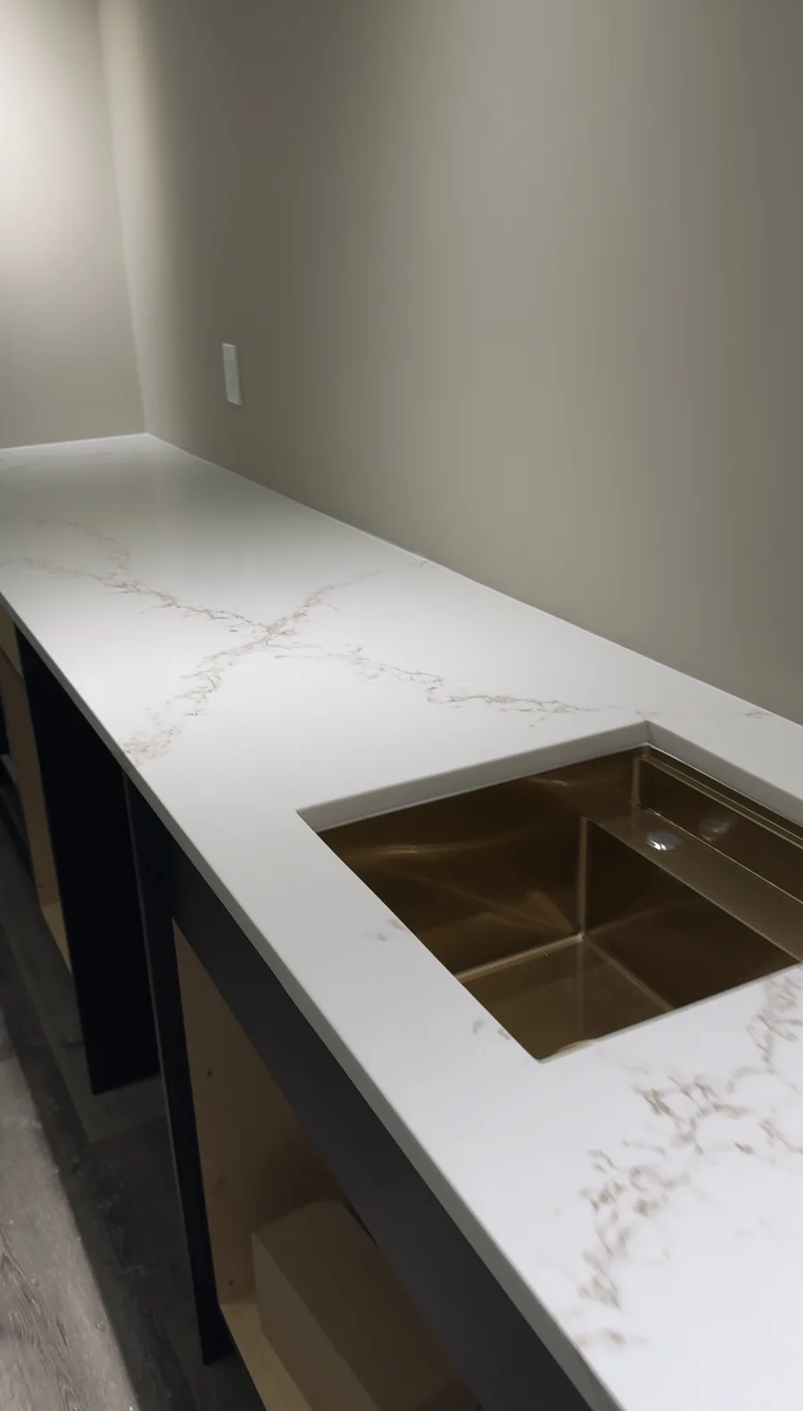 Finished bar close-up — white quartz countertop with integrated gold undermount bar sink, dark lower cabinetry