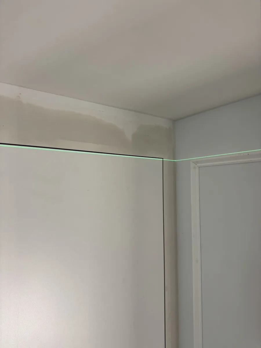 King of Prussia basement before renovation — bathroom rough-in area with wall framing, exposed plumbing, laser-level alignment mark on concrete block