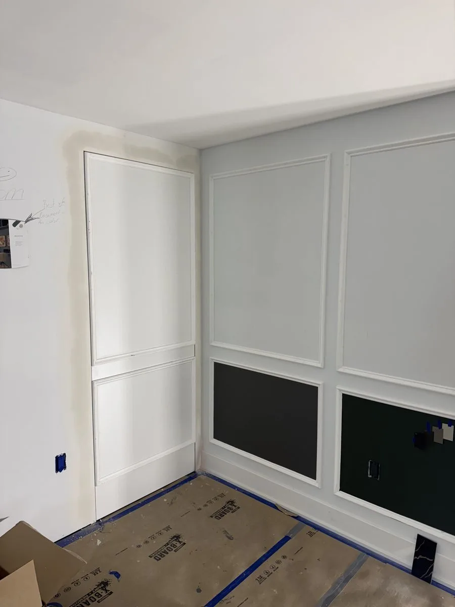 During construction — hidden utility room door and decorative wall moulding panels being installed