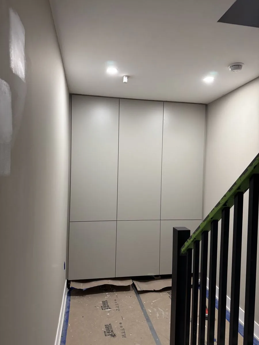 During construction — staircase view showing custom storage wall and premium black railing installation
