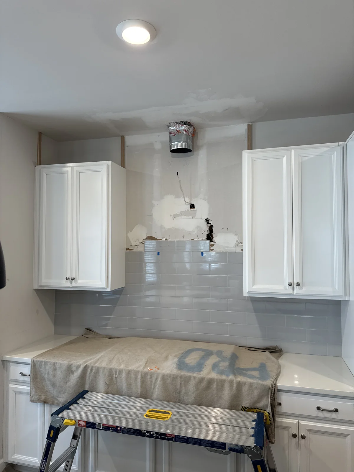 Kitchen range area before renovation — open duct cavity, wide angle view of damaged drywall and partial tile, West Chester PA