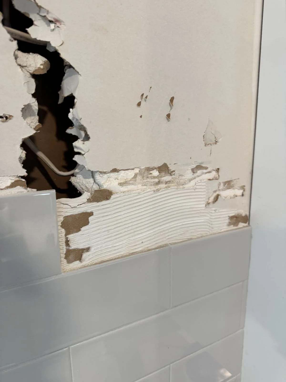 Drywall hole closeup at kitchen range position before renovation — West Chester PA